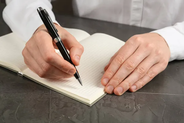 Чоловік Пише Ручкою Блокноті Сірим Столом Крупним Планом Руки — стокове фото