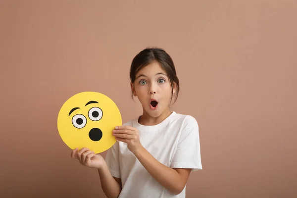 Petite Fille Émotionnelle Tenant Visage Avec Emoji Choqué Sur Fond — Photo