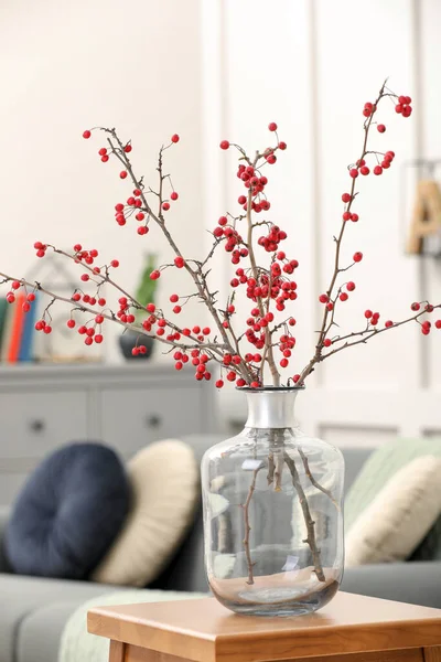 Stock image Hawthorn branches with red berries on wooden table in living room