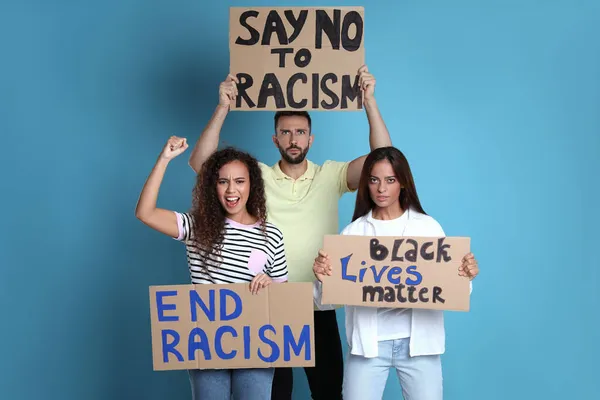 示威者在浅蓝色背景下展示不同的反种族主义口号 拿着标语牌的人 — 图库照片