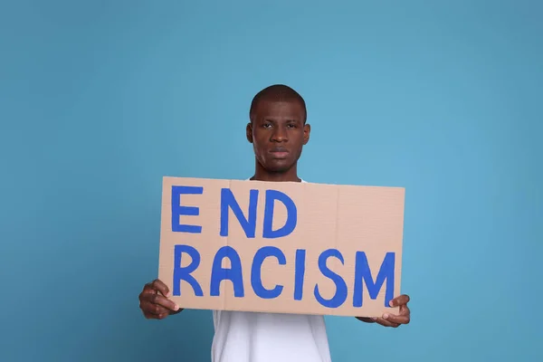 アフリカ系アメリカ人男性がライトブルーの背景にフレーズで署名 End Racism — ストック写真