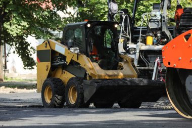 Şehir caddesinde modern patinaj yükleyicisi. Yol onarım servisi