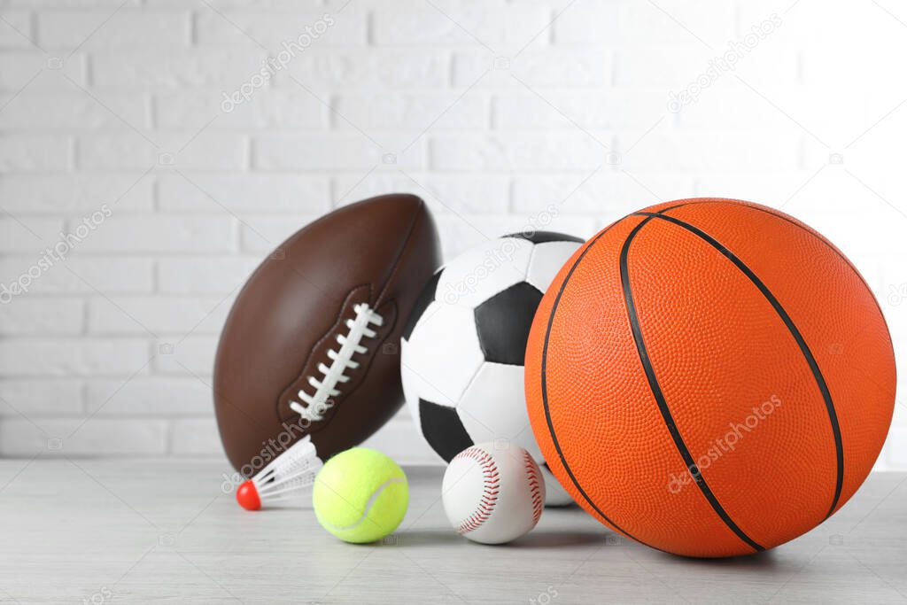 Set of different sport balls and shuttlecock on light wooden table