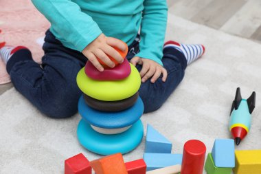 Küçük çocuk halıdaki oyuncaklarla oynuyor, yakın plan.