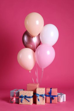 Pembe arka planda bir sürü hediye kutusu ve balon var.