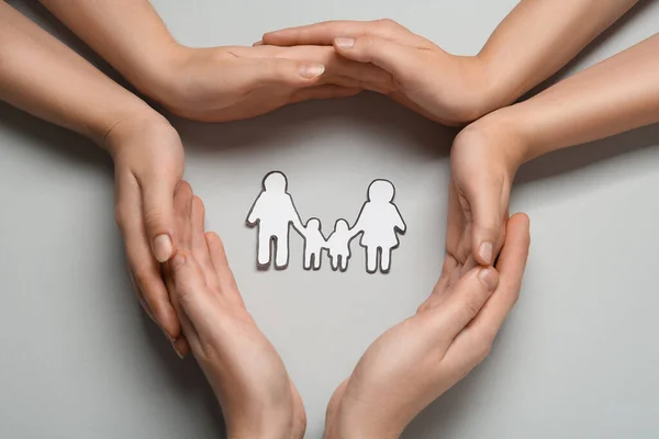 People with paper family cutout on light grey background, top view