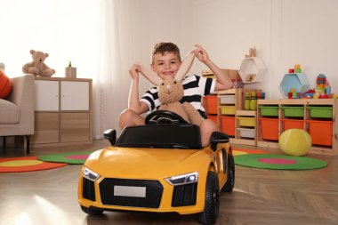 Küçük şirin çocuk evde oyuncak tavşan ve büyük oyuncak arabayla oynuyor.