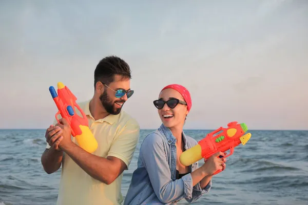 Pareja Feliz Con Pistolas Agua Cerca Del Mar Atardecer — Foto de Stock