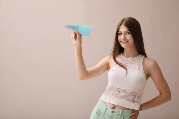 ベージュの背景に紙飛行機と美しい十代の女の子 テキストのスペース — ストック写真