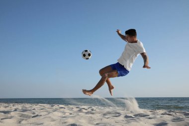 Sahilde futbol oynayan bir adam.