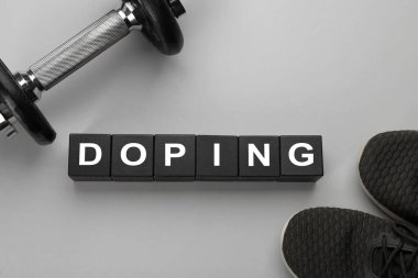 Açık gri zemin üzerinde Doping, dambıl ve spor ayakkabıları olan siyah tahta küpleri, düz yatıyordu.