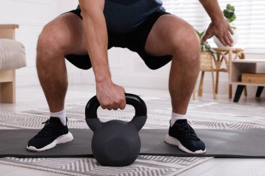 Evde kettlebell ile kaslı adam eğitimi, yakın plan.