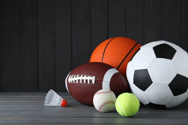 グレーの木製テーブルの上に異なるスポーツボールとシャトルトックのセット — ストック写真