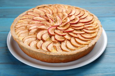 Açık mavi ahşap masada lezzetli elmalı turta.