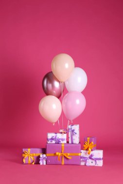 Pembe arka planda bir sürü hediye kutusu ve balon var.