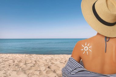 Kumsalda güneş kremi sürmüş genç bir kadın, mesaj için yer var.