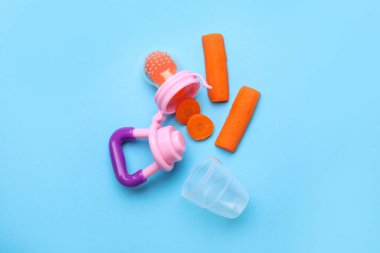 Açık mavi arka planda haşlanmış havuçlu Nibbler, düz yatıyordu. Bebek besleyicisi