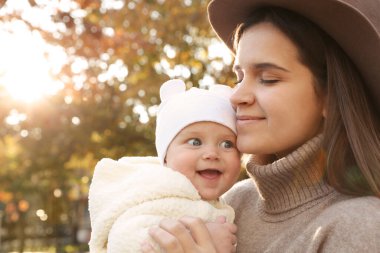 Mutlu anne ve küçük kızı sonbahar günü açık havada mesajlaşmak için yer ararlar.