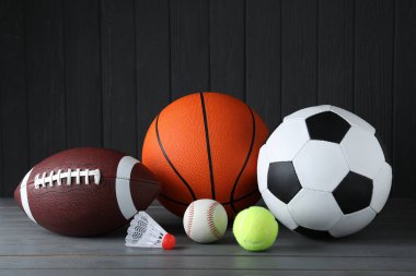 Gri ahşap masada farklı spor topları ve mekik aletleri.