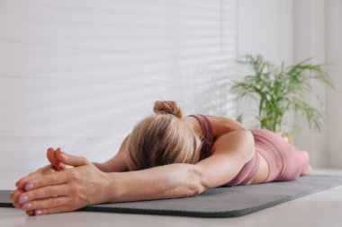 Evde yerde yoga yapan bir kadın.