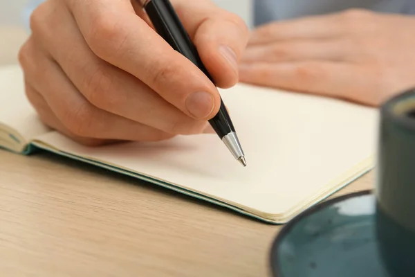ライト木製のテーブルでノートにペンで書く男は 手を閉じて — ストック写真