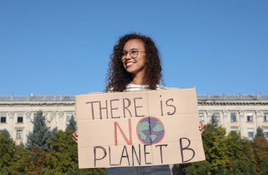 Afro-Amerikalı genç bir kadın açık havada iklim değişikliğini protesto ediyor.