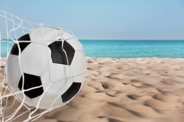 Deniz kenarındaki kumlu sahilde futbol topu ağda. Plaj futbolu