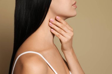 Young woman doing thyroid self examination on beige background, closeup clipart