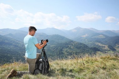 Profesyonel fotoğrafçı dağlarda modern kamerayla fotoğraf çekiyor. Metin için boşluk