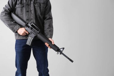 Saldırı silahı var. Hafif arka planda tüfekli adam, yakın plan. Metin için boşluk
