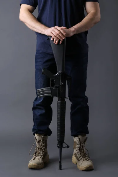 Assault gun. Man holding rifle on dark background, closeup