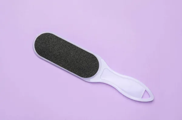 Foot file on violet background, top view. Pedicure tool