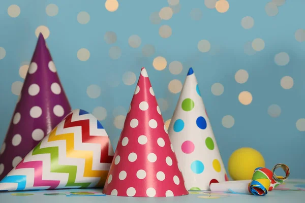 Chapéus Coloridos Itens Festivos Mesa Contra Fundo Azul Com Luzes — Fotografia de Stock