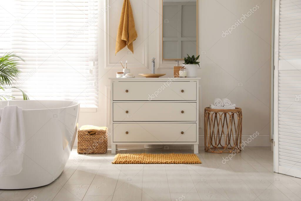 Stylish orange mat near chest of drawers in bathroom