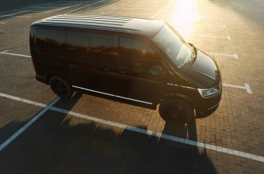 Gün batımında park yerinde siyah bir minibüs.