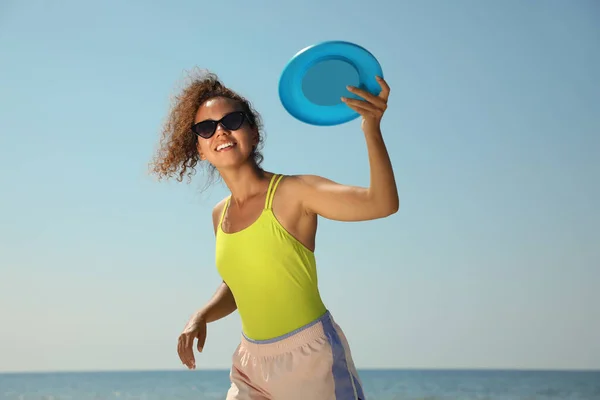 幸せなアフリカ系アメリカ人女性が晴れた日にビーチでディスクを投げる — ストック写真
