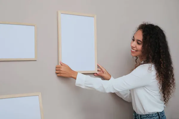 Gelukkig Afro Amerikaanse Vrouw Opknoping Lege Frame Bleke Roos Muur — Stockfoto