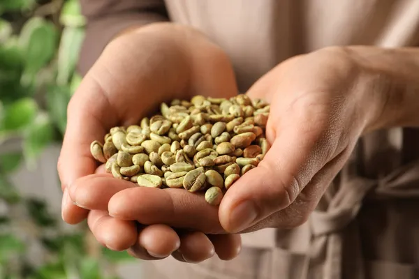 Vrouw Houden Stapel Van Groene Koffiebonen Wazig Achtergrond Close — Stockfoto