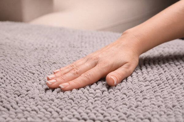 Woman touching soft grey fabric indoors, closeup