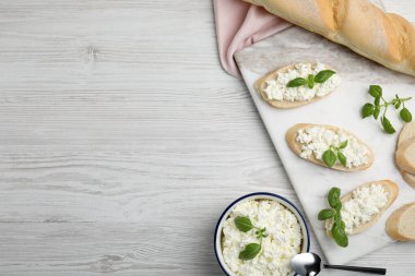 Süzme peynirli ekmek ve fesleğenli beyaz ahşap masa, düz yatak. Metin için boşluk