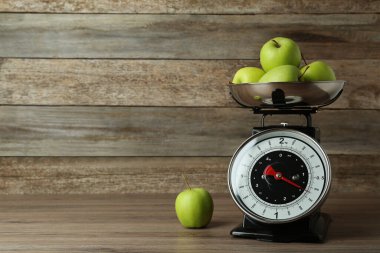 Mutfak terazisi ve ahşap masada yeşil elmalar. Metin için boşluk