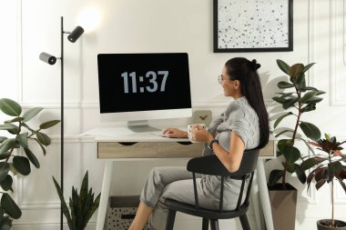 Işık odasındaki masada çay içen genç bir kadın. Merkez Ofis