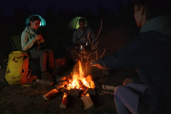 夜のキャンプでたき火の近くに座っている人 — ストック写真