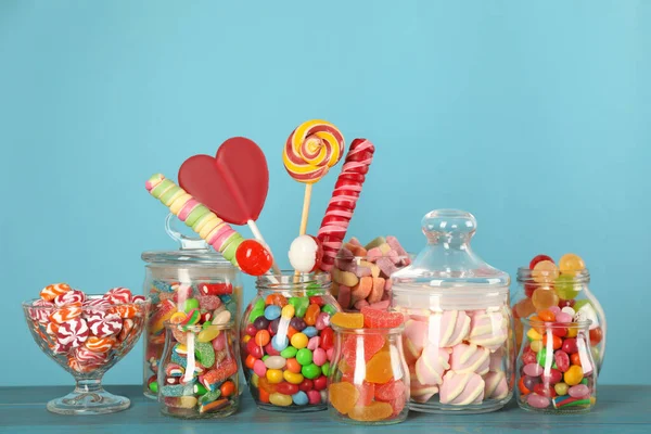 Üvegek Különböző Ízletes Cukorkákkal Türkiz Asztalon — Stock Fotó