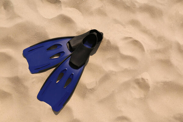 Pair of blue flippers on sand, top view. Space for text