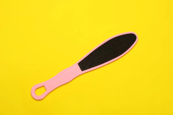 Pink foot file on yellow background, top view. Pedicure tool
