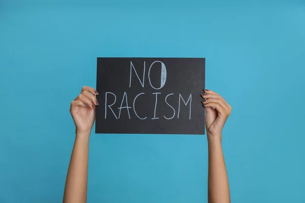 Γυναίκα Κρατώντας Πινακίδα Φράση Racism Light Blue Background Closeup — Φωτογραφία Αρχείου