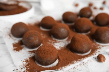 Lezzetli çikolatalı trüf mantarı. Beyaz masa üzerinde kakao tozu. Yakın plan.