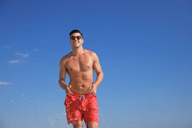 Mavi gökyüzüne karşı çekici vücutlu yakışıklı bir adam.