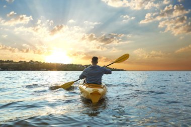 Gün batımında gölde kayak yapan bir adam, arka manzara. Yaz etkinliği